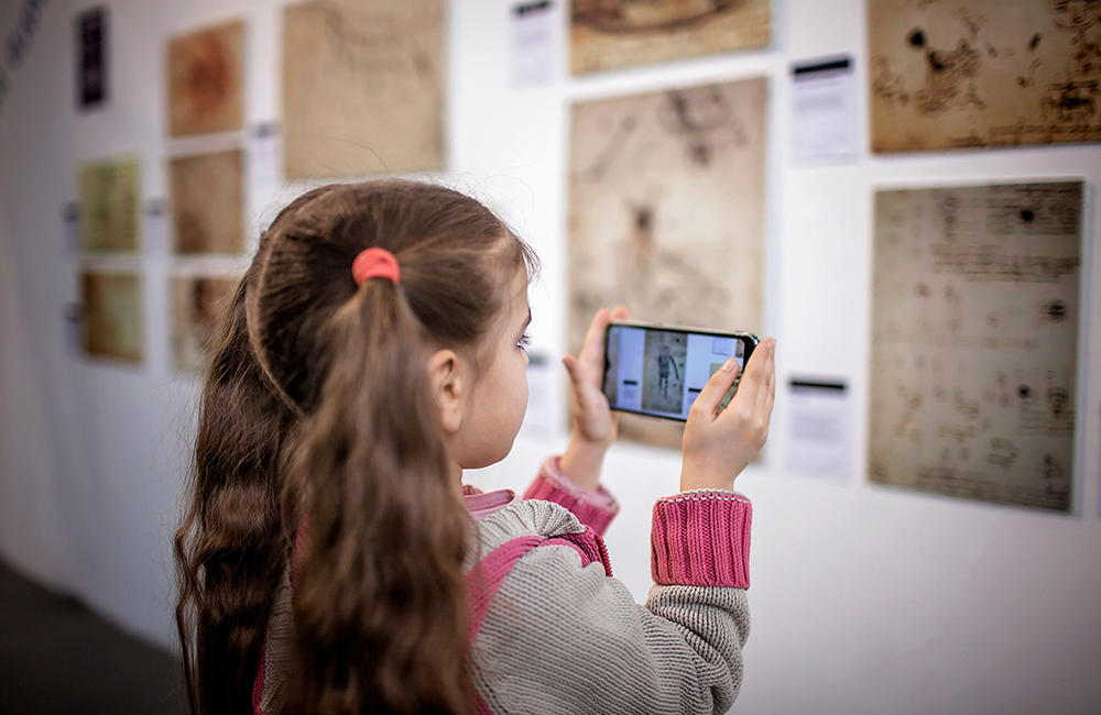 A young girl using her smartphone to scan an inscription in a museum